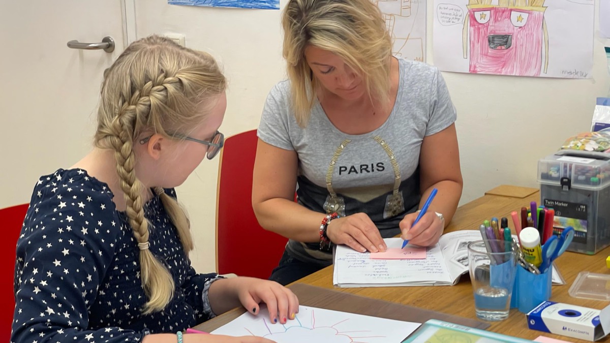 Trainerin und Schülerin arbeiten gemeinsam an einem Tisch mit Lernmaterialien